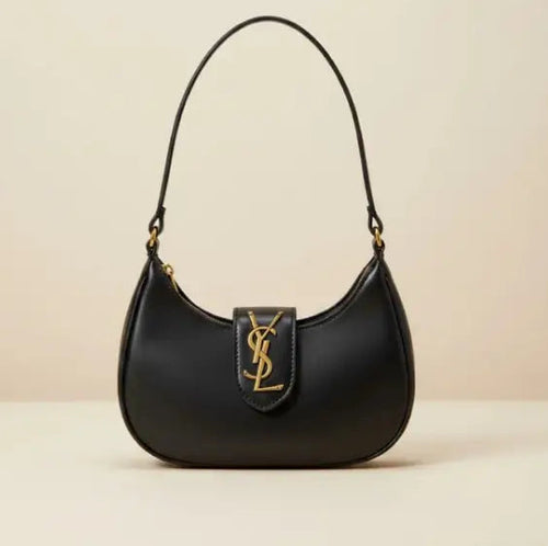 Black handbag with a gold logo on a beige background